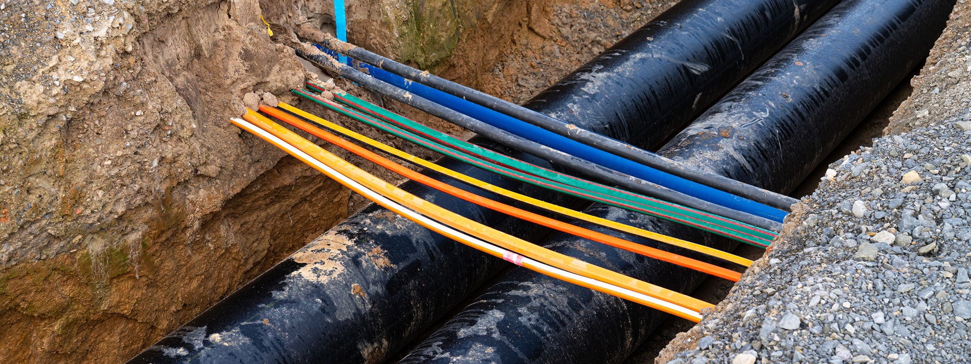 Trench With Two Laid Heating Pipes. Electrical Cables Cross The Trench.
