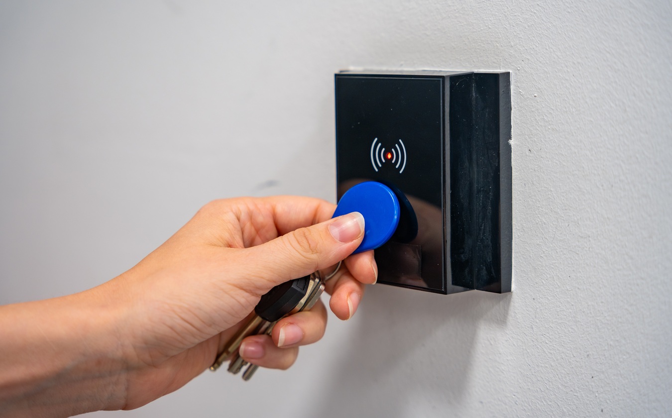 Person Using Contactless Key Fob On Indoor Access Control Reader. Secure Building Access Protects Restricted Areas And Residential Facilities